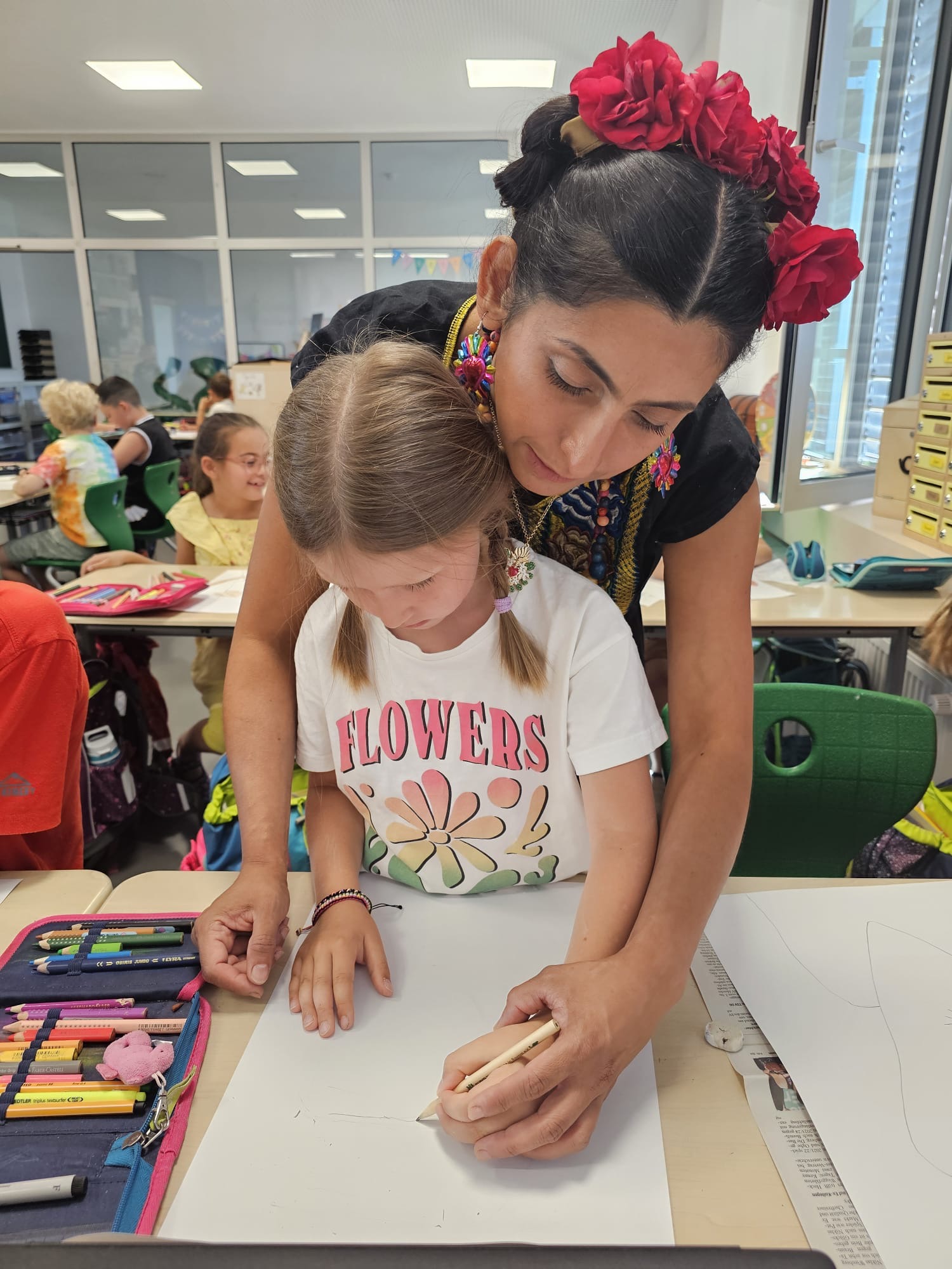 Lizeth hilft einem Kind beim Malen